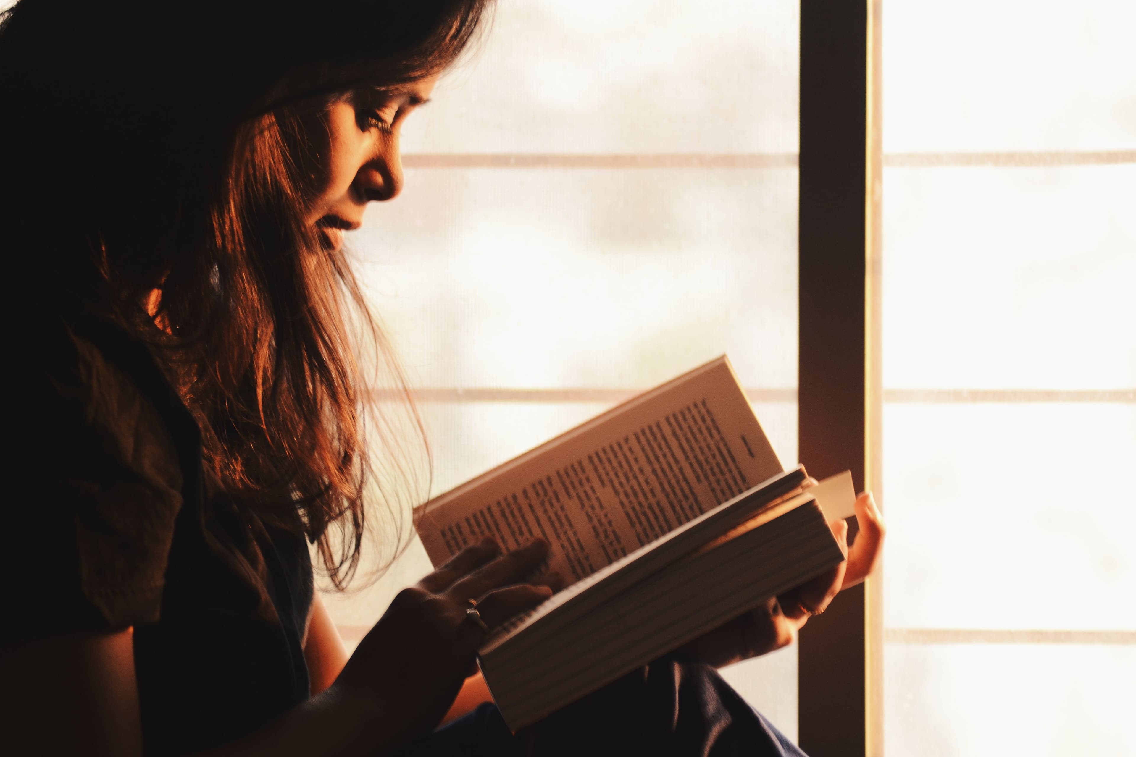 Female Quran teacher reading the Quran in soft window light